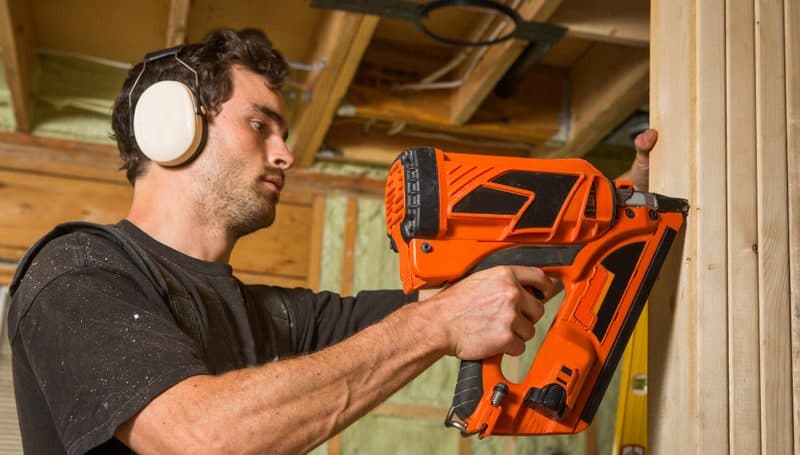 Carpenter using a nail gun on timber wall framing