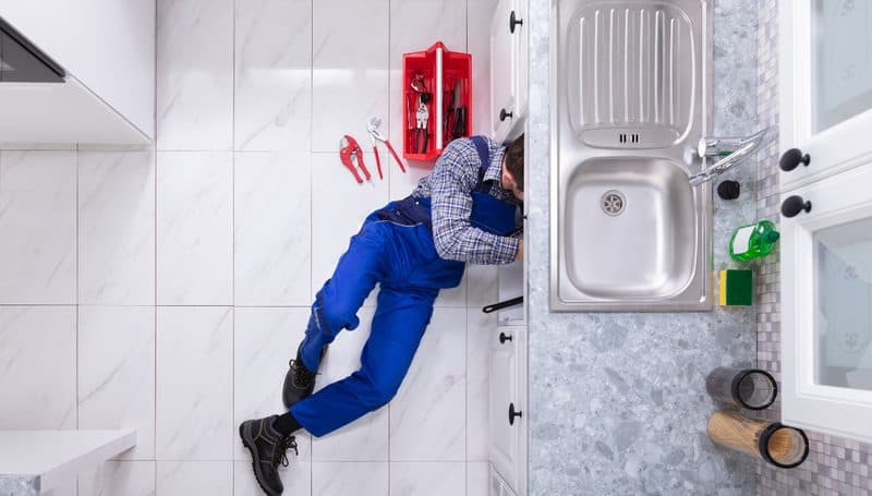 Plumber working under a kitchen sink
