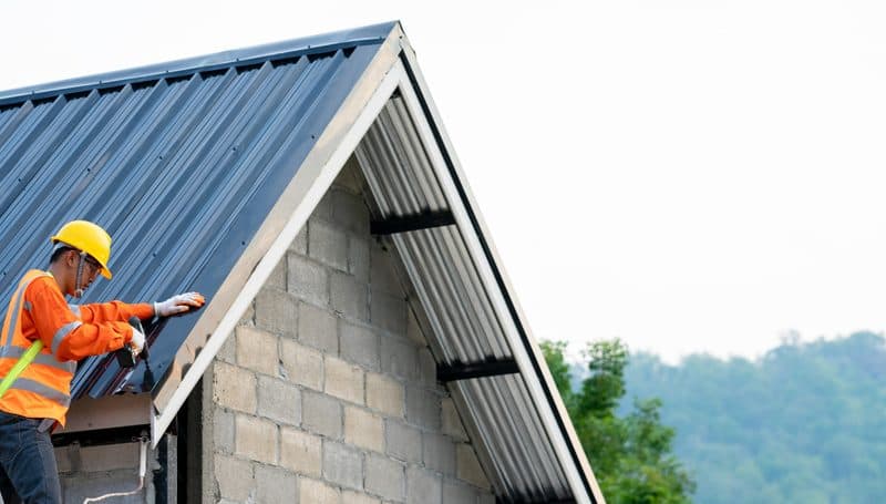 Roofer fixing sheeting on a metal roof